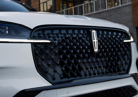 The black grille of a white 2025 Lincoln Aviator® SUV is shown with its fog lights on. | Parkway Lincoln in Winston Salem NC