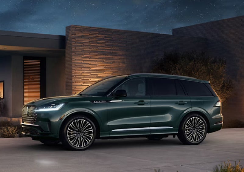 A green 2027 Lincoln Aviator® SUV is parked outside a contemporary home. | Parkway Lincoln in Winston Salem NC