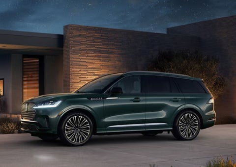 A green 2027 Lincoln Aviator® SUV is parked outside a contemporary home. | Parkway Lincoln in Winston Salem NC