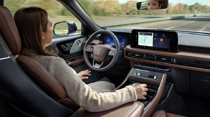 A 2027 Lincoln Aviator® SUV is being driven hands-free on a highway lined with trees. | Parkway Lincoln in Winston Salem NC