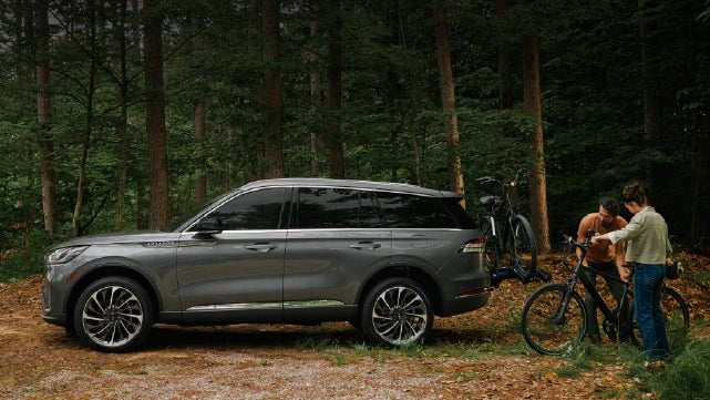 A father and son load e-bikes on a bike rack attached to a 2027 Lincoln Aviator® SUV. | Parkway Lincoln in Winston Salem NC