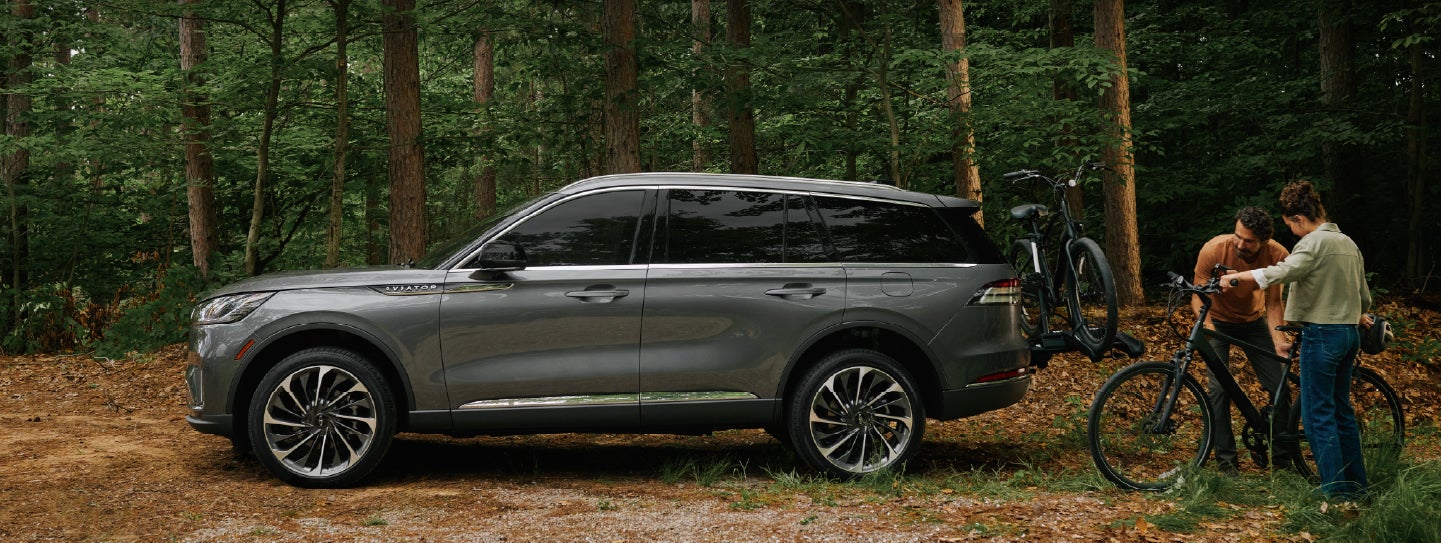 A father and son load e-bikes on a bike rack attached to a 2027 Lincoln Aviator® SUV. | Parkway Lincoln in Winston Salem NC