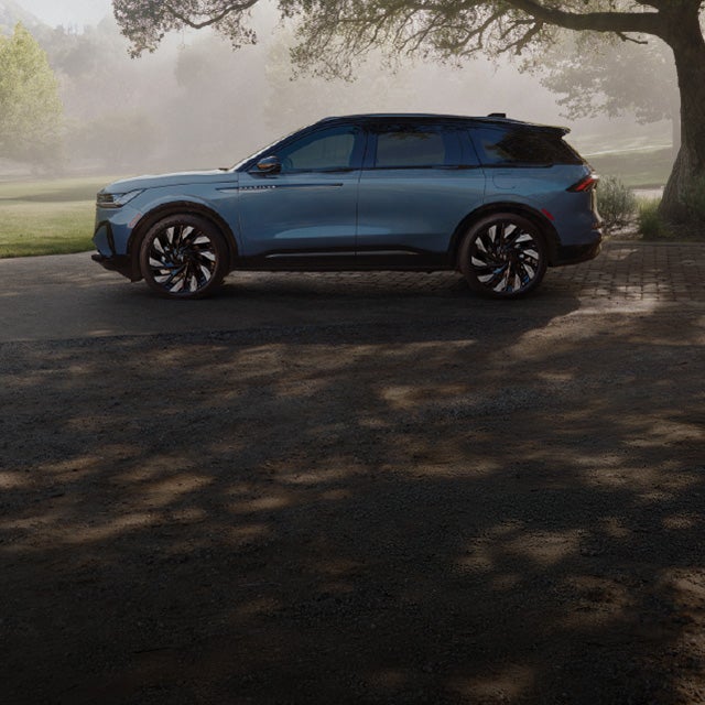 A 2026 Lincoln Nautilus® SUV parked beneath a large tree in a park landscape.