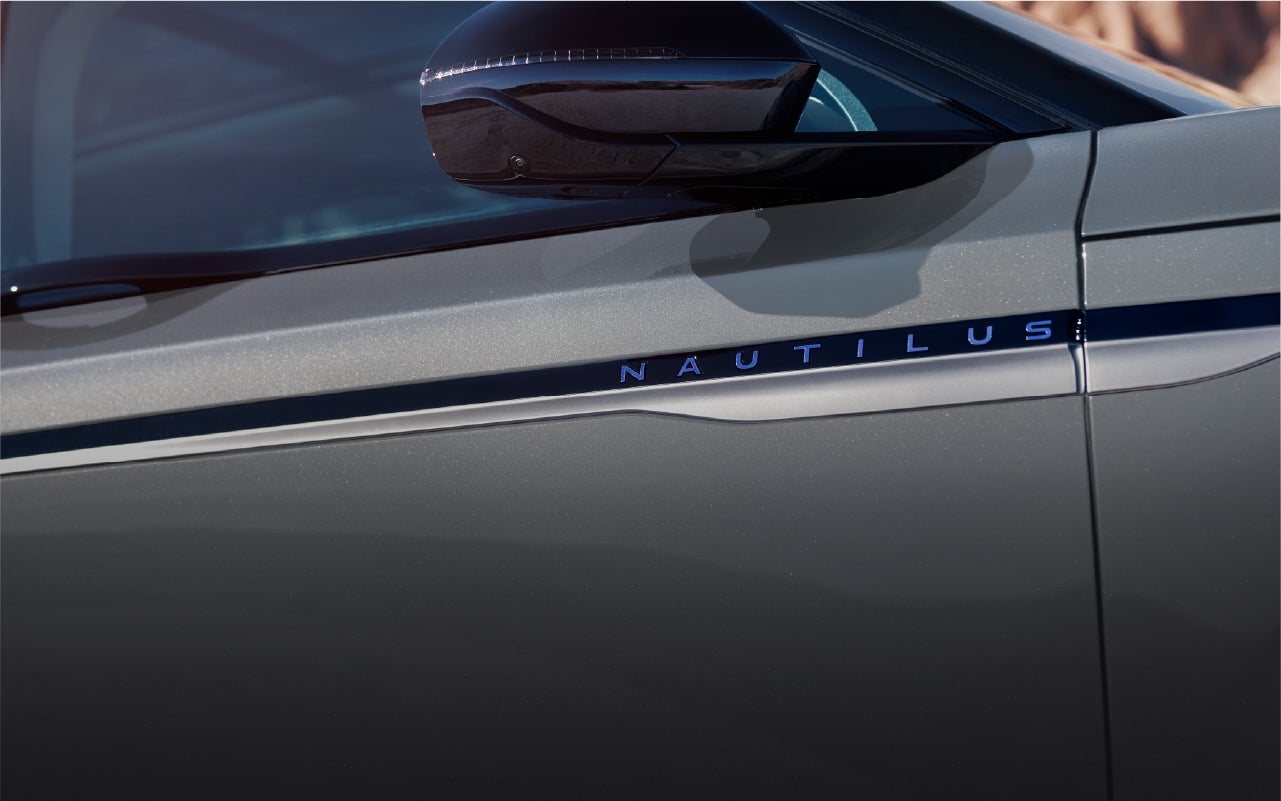A close-up of the 2026 Lincoln Nautilus® Reserve Hybrid exterior showing the front door accent and sculpted body panel beneath the side mirror.