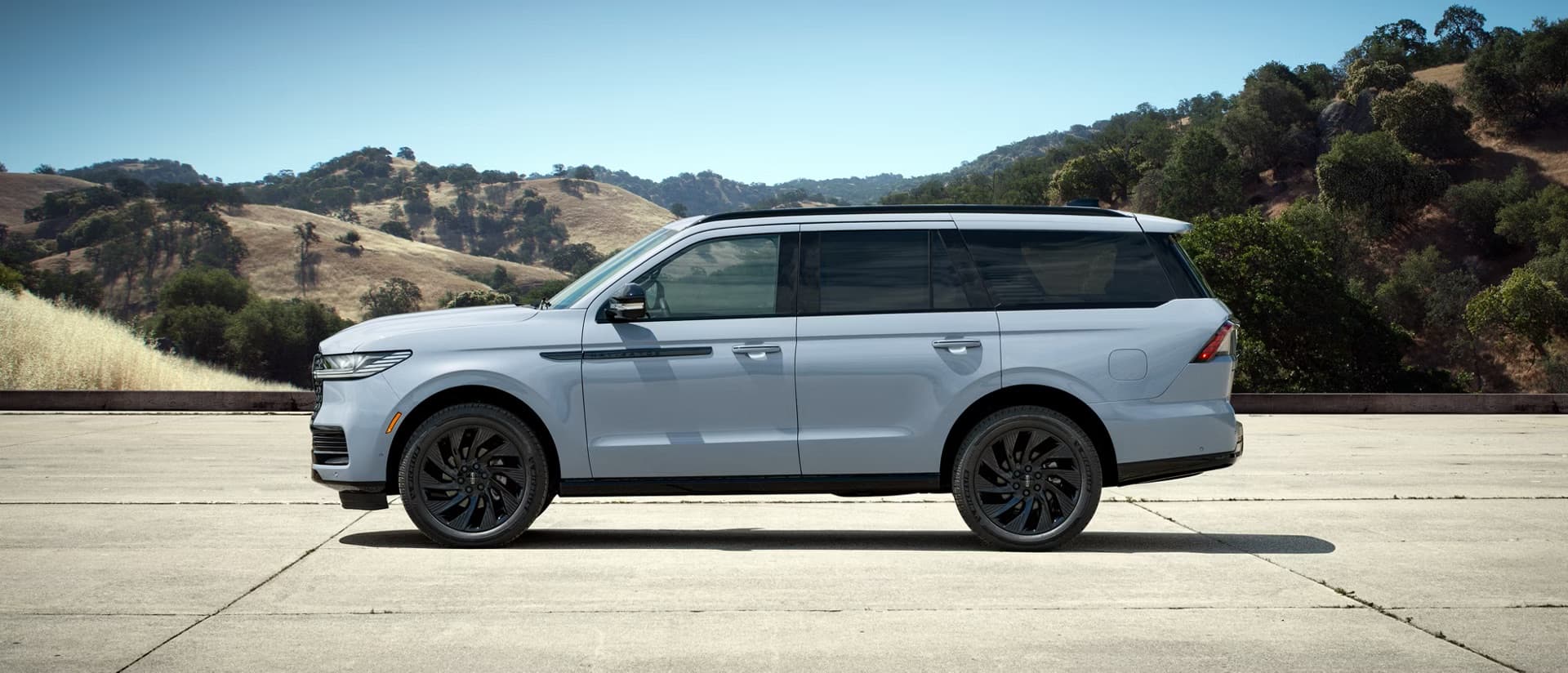  A matte grey 2027 Lincoln Navigator parked in a parking lot in front of mountains. 